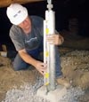 A contractor installing crawl space support posts under a home